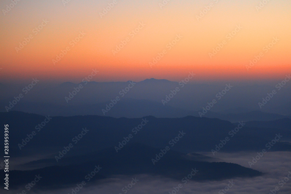 Beautiful golden natural sunlight and twiligh of sunrise shining to in the mist on valley of mountain in Thailand
