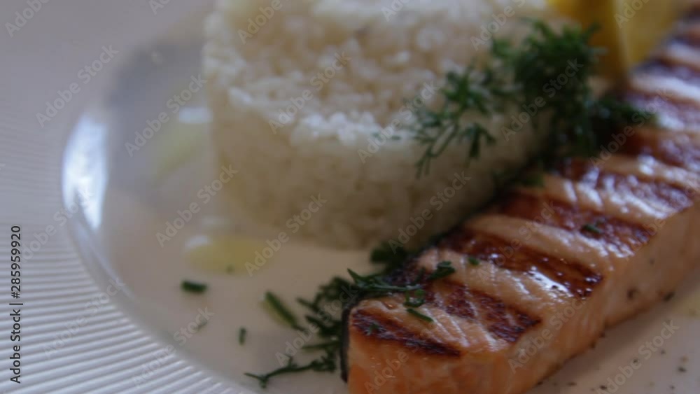 grilled red fish, served with rice and lemon. high protein foods. the camera moves around this to the right. close-up grilled red fish, served with rice and lemon. high protein foods. the camera moves around this to the right. close-up