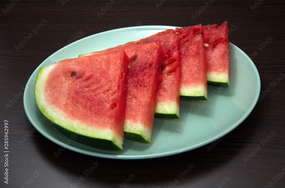 Slices of chopped watermelon are laid out on a large plate Slices of chopped watermelon are laid out on a large plate
