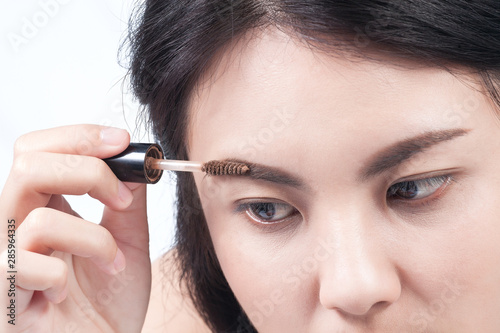 Closeup face young woman applying blusher on eyebrow.