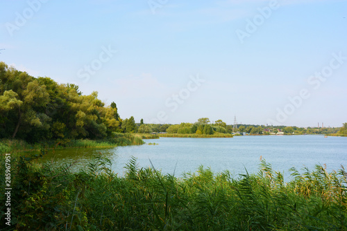 Beautiful view of the Samara River with picturesque steep banks and coast  trees  greenery and rich sky. Bright and unforgettable nature in the housing estate  Shevchenko  Dnipro  Ukraine.