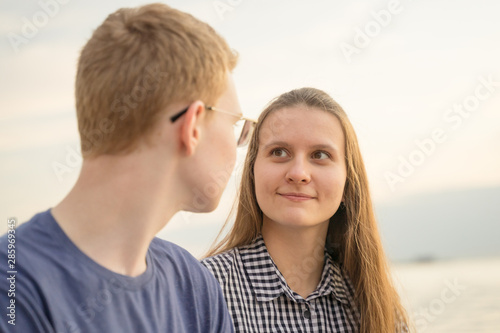 Girl looking at boy on a beach at the sunset, concept of teen love