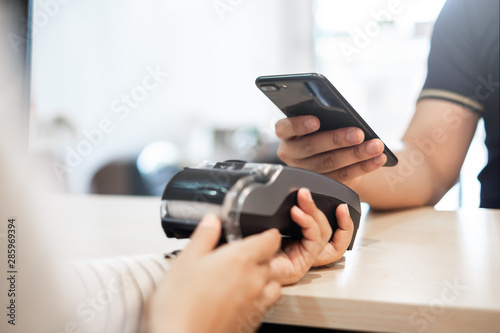 Customer using phone for payment to owner at cafe restaurant, cashless technology and credit card payment concept photo