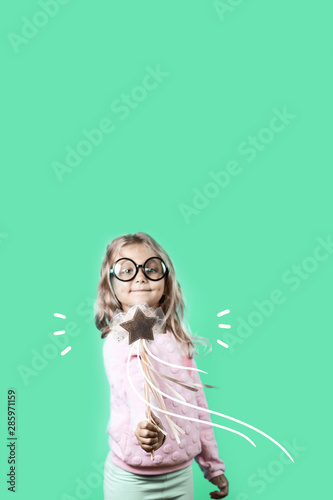 girl with glasses and a magic wand says a spell on green background