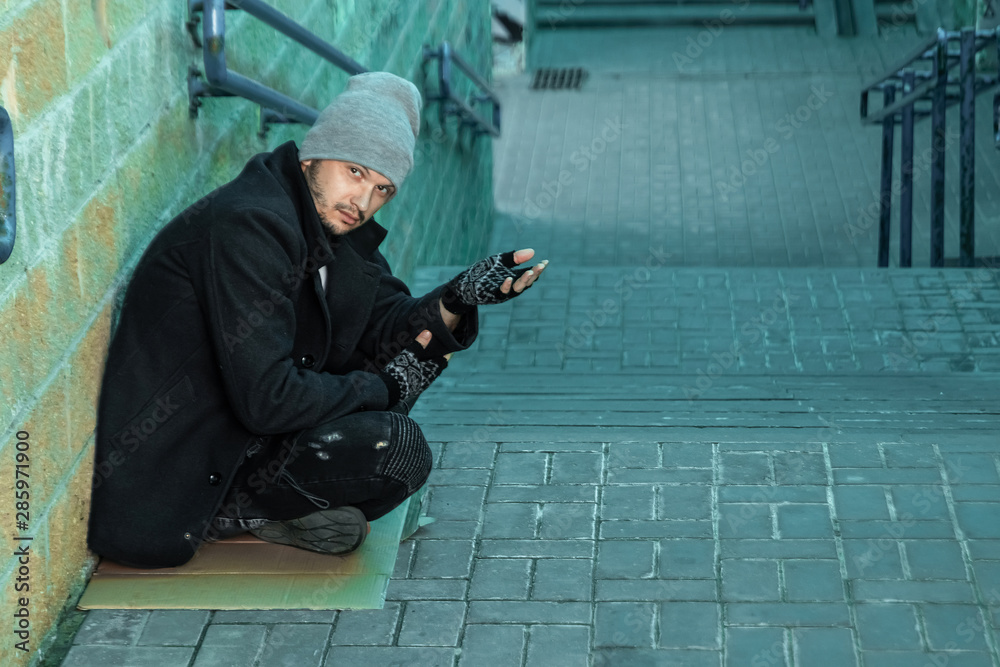 A man, homeless, a man asks for alms on the street. Concept of homeless person, addict, poverty, despair. A man, homeless, a man asks for alms on the street. Concept of homeless person, addict, poverty, despair.