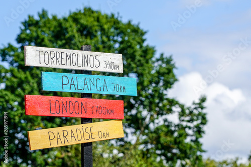 Signpost with plates with inscriptions about the distances to different cities and paradise © Zigmunds