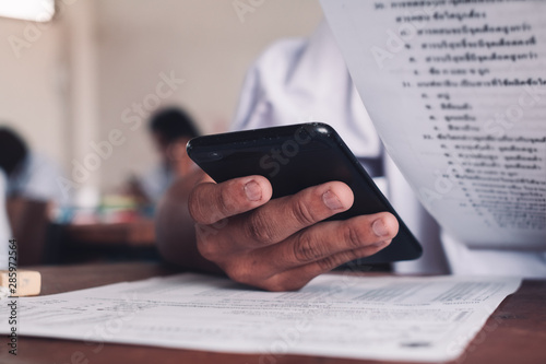 Foto Exam with uniform school student doing educational test with using smartphone