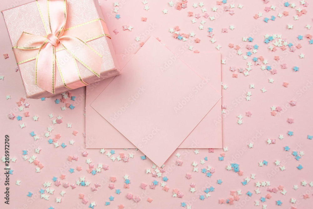 Layout for recording. Pink sheet for writing and a gift box on a pink background with decorative multi-colored elements with stars and bows. Flat lay, top view Layout for recording. Pink sheet for writing and a gift box on a pink background with decorative multi-colored elements with stars and bows. Flat lay, top view