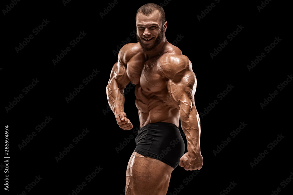 Muscular man showing muscles, isolated on the black background. Bodybuilder male naked torso abs