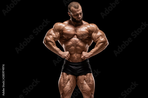 Muscular man showing muscles, isolated on the black background. Bodybuilder male naked torso abs