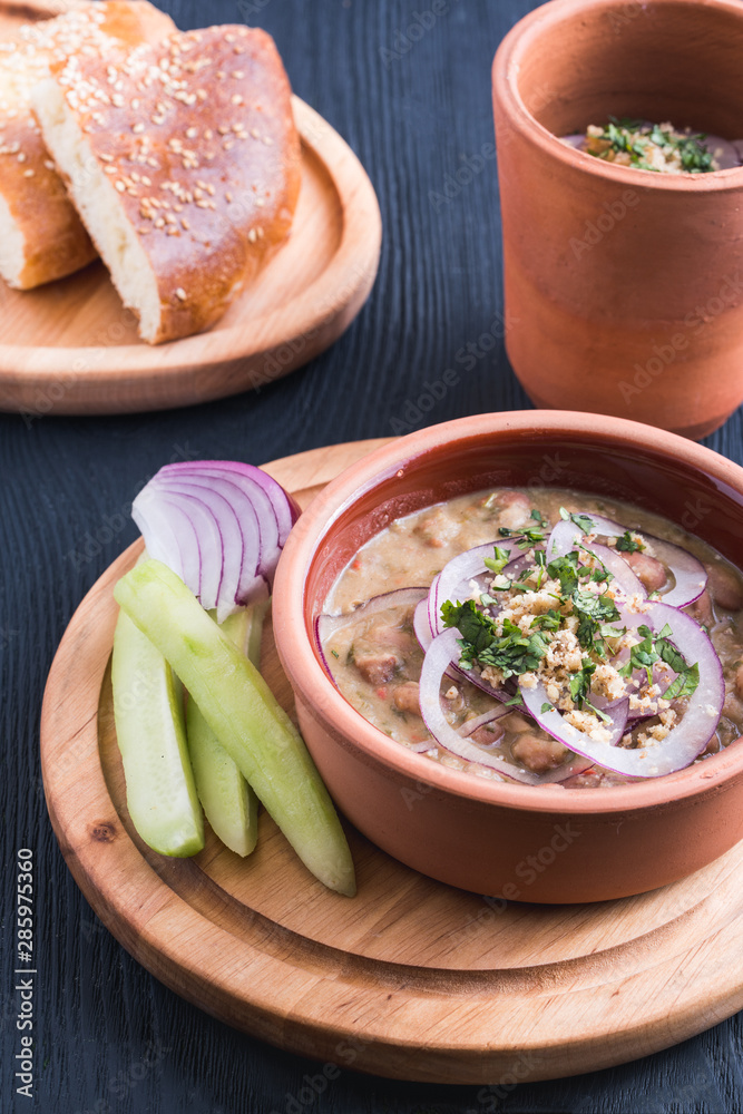 Georgian beef-walnut soup with fresh herbs, decorated with onion and cucumbers
