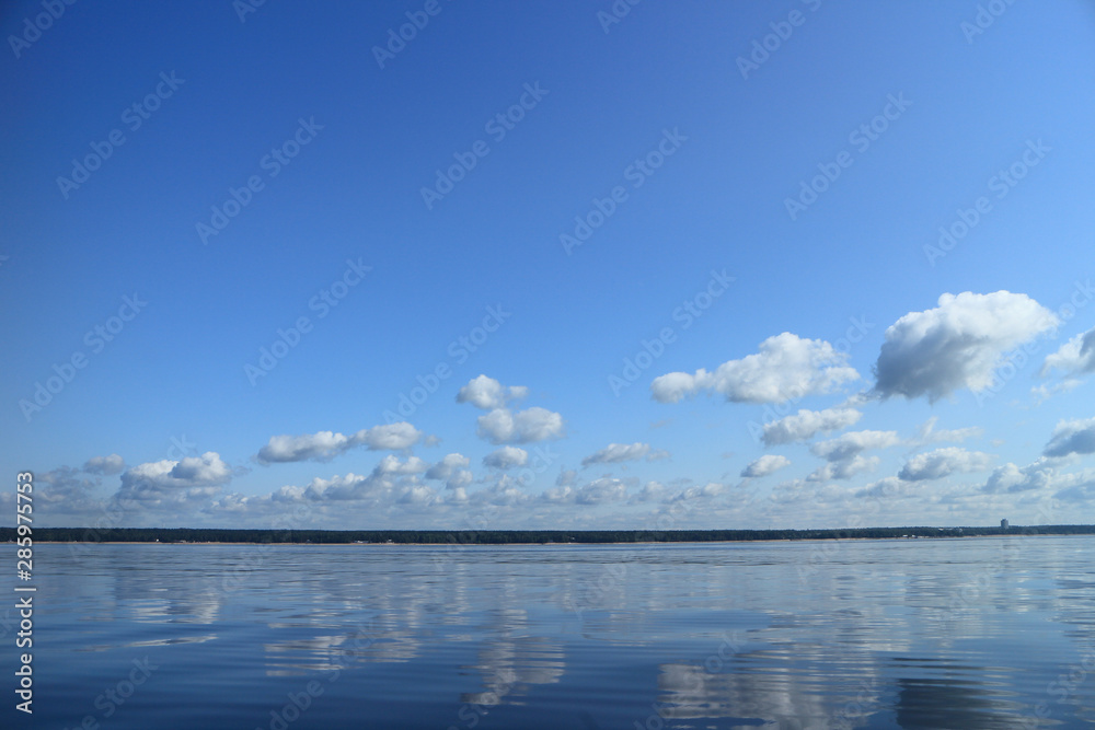 seascape, sea reflects blue sky with clouds