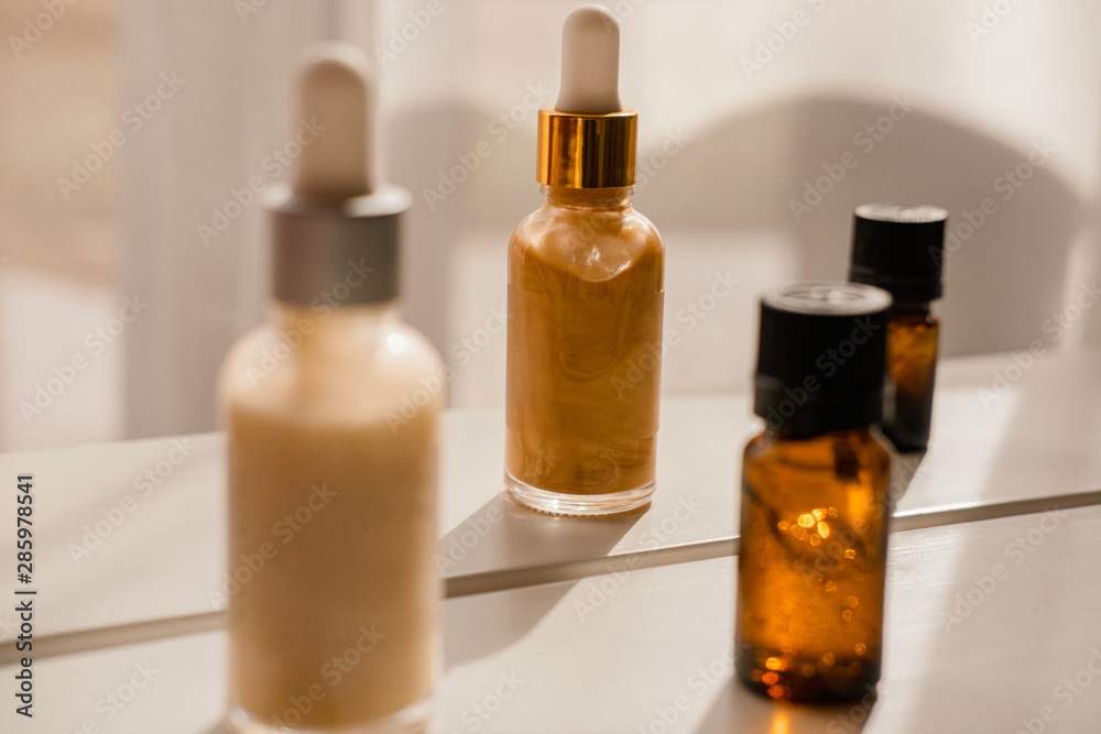 Glass bottles with dropper pipettes. Luminous and luxury gold and white liquid highlighter drops. Beauty blogger essentials. Minimalism package, branding mockup. Direct sun light Glass bottles with dropper pipettes. Luminous and luxury gold and white liquid highlighter drops. Beauty blogger essentials. Minimalism package, branding mockup. Direct sun light