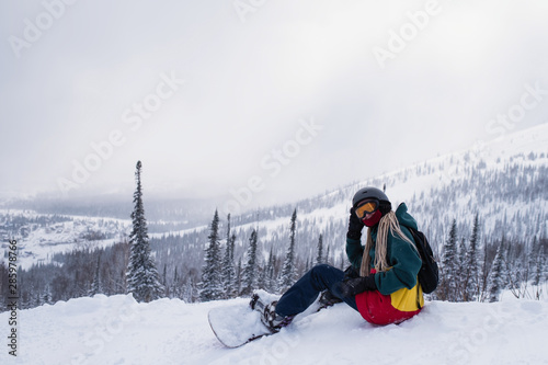 Freerider woman with snowboard on a snowy slope in mountains.