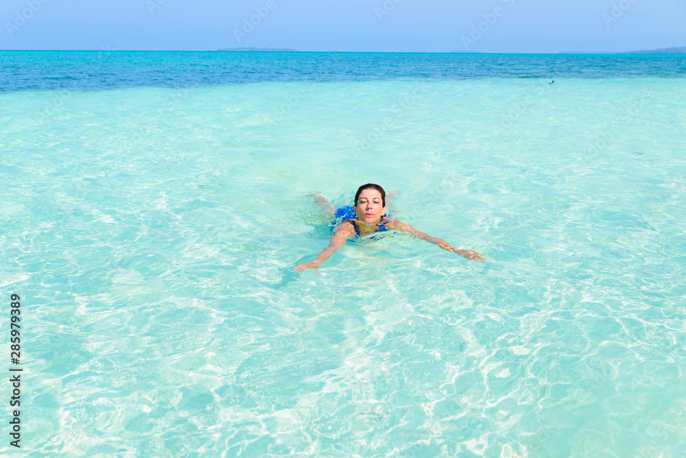 Woman swimming in caribbean sea turquoise transparent water. Tropical beach in the Kei Islands Moluccas, summer tourist destination in Indonesia.