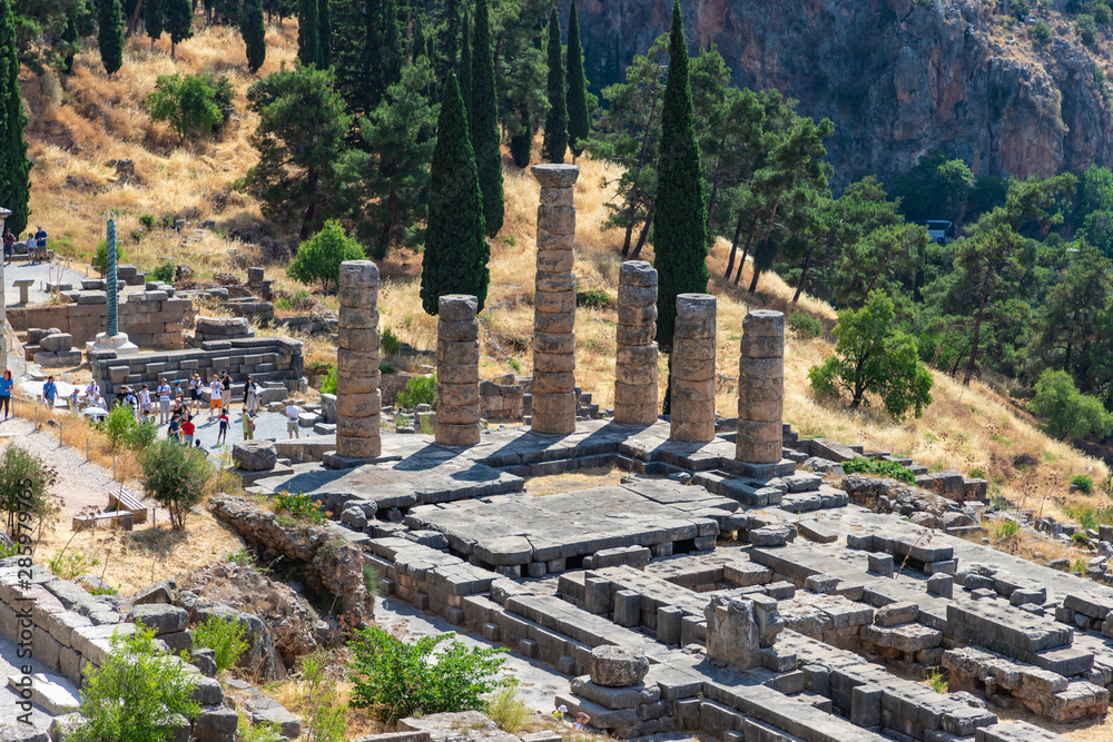 DELPHI / GREECE - JUNE 29, 2019: Apollo Temple in Delphi archaeological site at the Mount Parnassus. Delphi is famous by the oracle at the sanctuary dedicated to Apollo.
