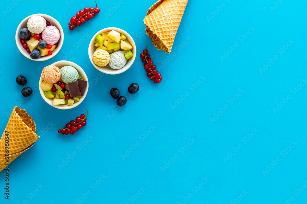 Gelato, waffle cone, berries, chocolate on blue background top view copyspace
