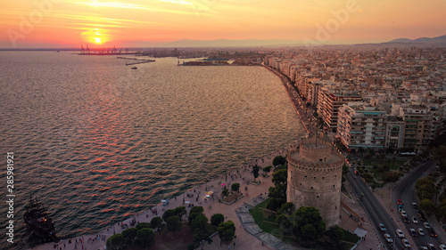 Aerial drone view of iconic historic landmark - old byzantine White Tower of Thessaloniki or Salonica at sunset with golden colours, North Greece