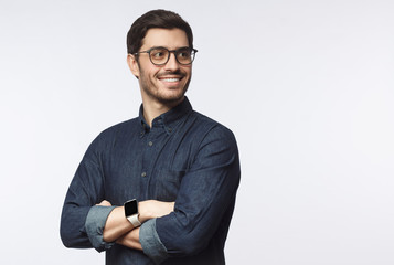 Young handsome business man dressed in casual denim shirt with smartwatch on wrist, isolated on gray background