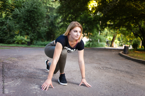young woman in low start position before jogging in park
