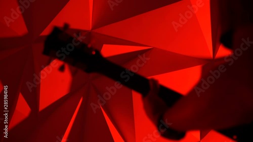 The musician plays the guitar. Rock guitarist silhouette on red background