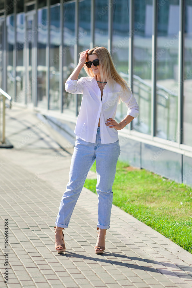 Street style fashion - lady in white shirt and boyfriend jeans walking along business centre