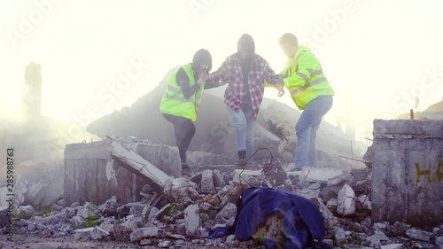 portrait rescuers in uniform help the victim of the earthquake ,pulling her out from under the ruins of the house
