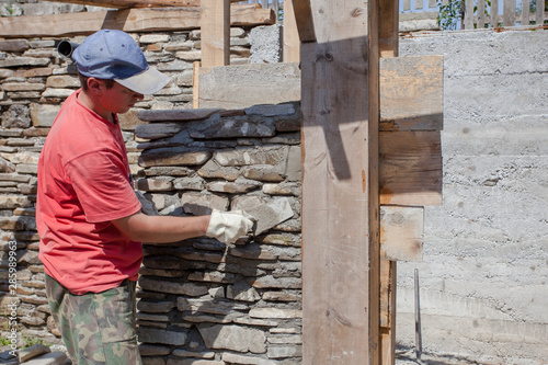 man with trowel for stone wall construction.