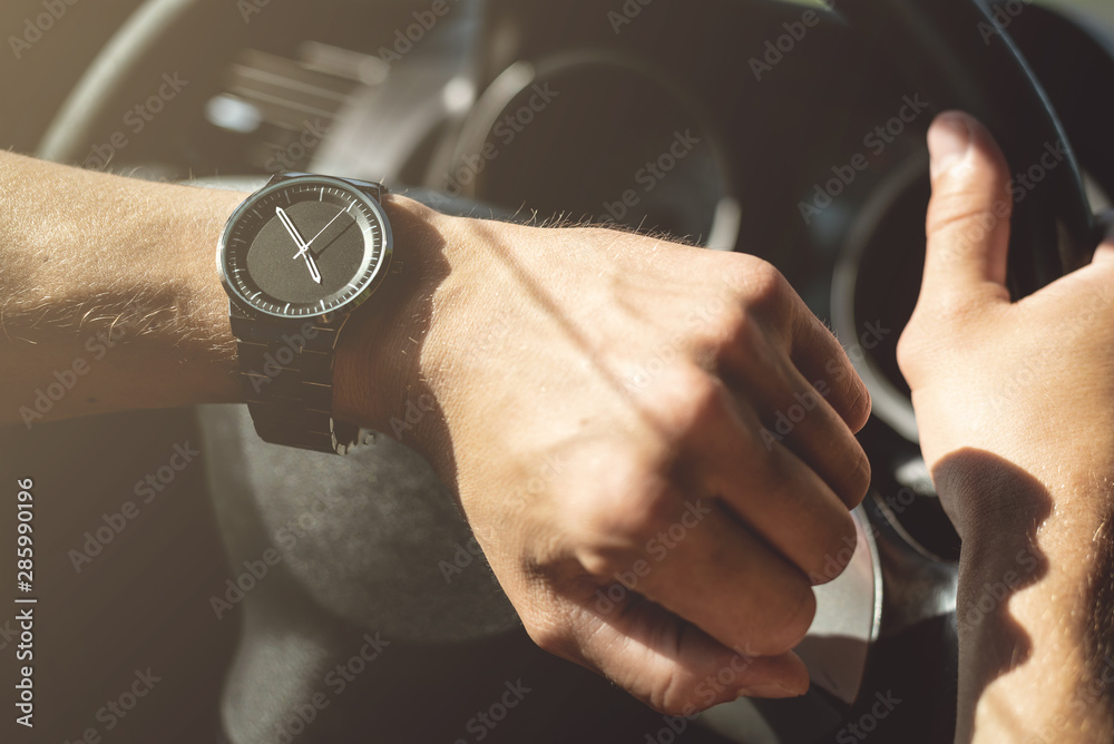Driver is checking a time on wrist watch on his hand. - obrazy, fototapety, plakaty 