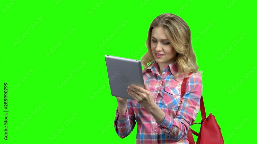 Charming woman using digital tablet on green screen. Cute girl in checkered shirt working on pc tablet with smile. Chroma key background. Charming woman using digital tablet on green screen. Cute girl in checkered shirt working on pc tablet with smile. Chroma key background.