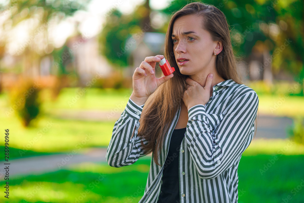 Asthmatic using inhaler from an asthma attack in park Asthmatic using inhaler from an asthma attack in park