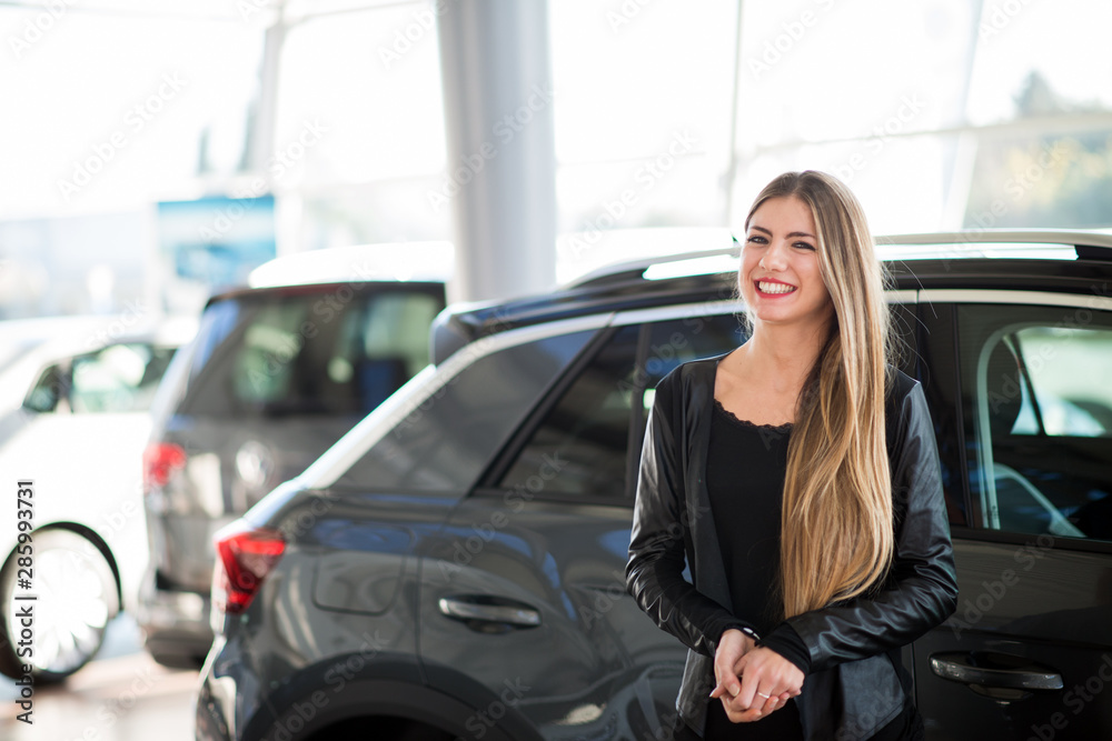 Smiling woman choosing her car at a car dealer