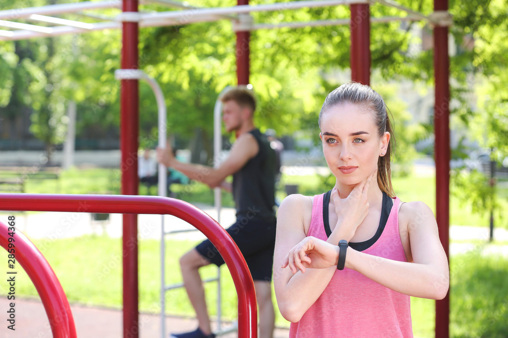 Obraz premium Sporty young woman checking her pulse outdoors