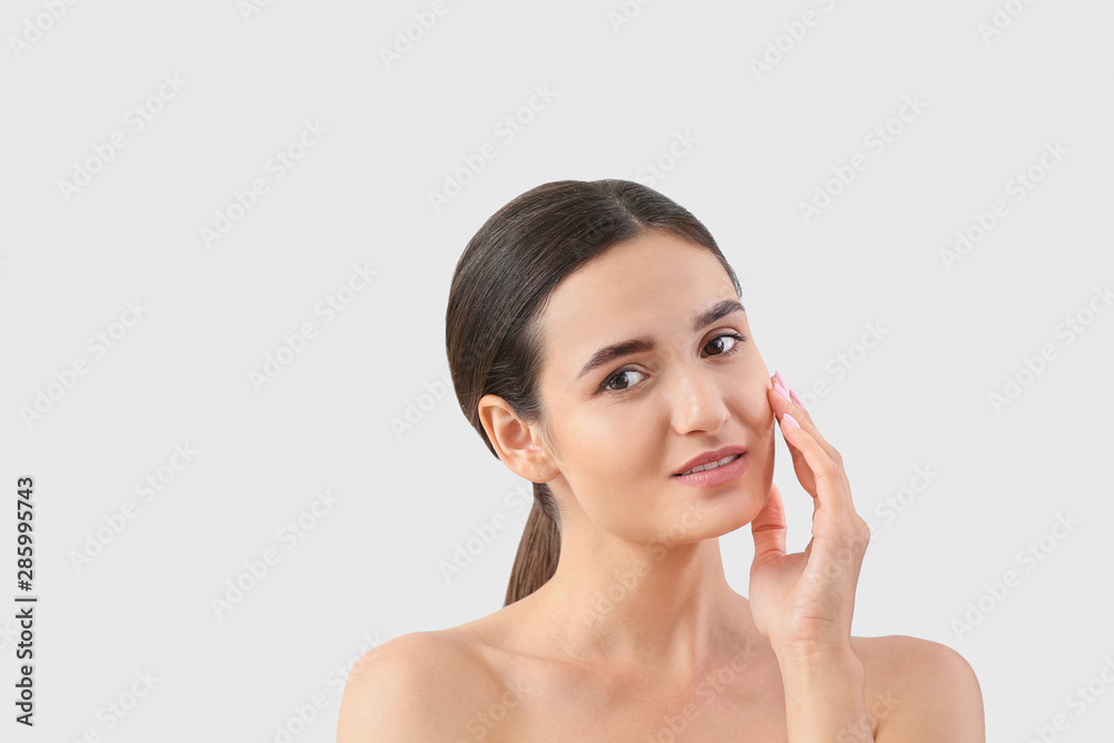 Young woman with beautiful eyebrows on light background