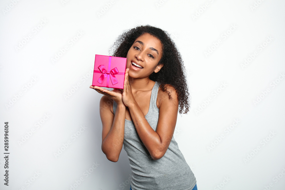 Portrait of beautiful African-American woman with gift box on white background Portrait of beautiful African-American woman with gift box on white background