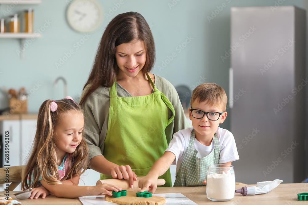 Woman and her little children preparing Christmas cookies at home Woman and her little children preparing Christmas cookies at home