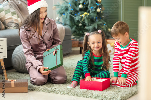Woman and her little children with Christmas gifts at home