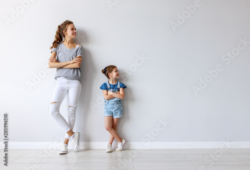 happy family mother (big sister) and child daughter near an empty wall.