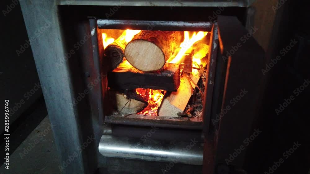 Man opens the door of the sauna stove and checks that woods burning well. After that closing the door again. Man opens the door of the sauna stove and checks that woods burning well. After that closing the door again.
