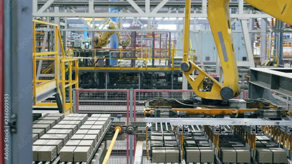 Modern plant with conveyor relocating bricks. Industrial Robots on an Assembly Line. Modern plant with conveyor relocating bricks. Industrial Robots on an Assembly Line.