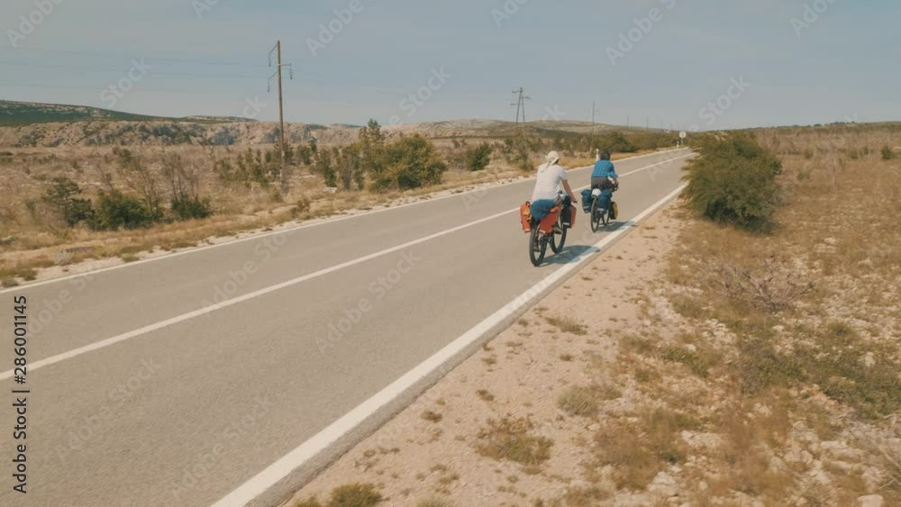 Friends cycling on a long deserted road Friends cycling on a long deserted road