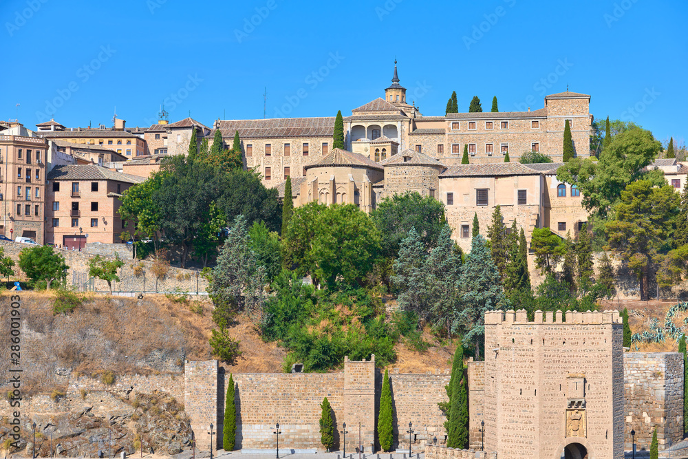 Colorful cityscape view of the Alcántara gate, the Conceptionists convent and Santa Cruz museum of the medieval walled city of Toledo, Castilla la Mancha, Spain. UNESCO world heritage site.