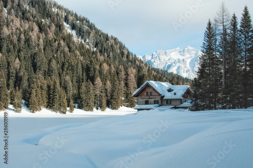 Wooden chalet by a snowy lake in winter in the Dolomites