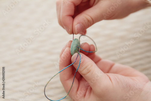 фотографія Child threading buttons onto a string to make jewelry; Fun craft for kids to cre