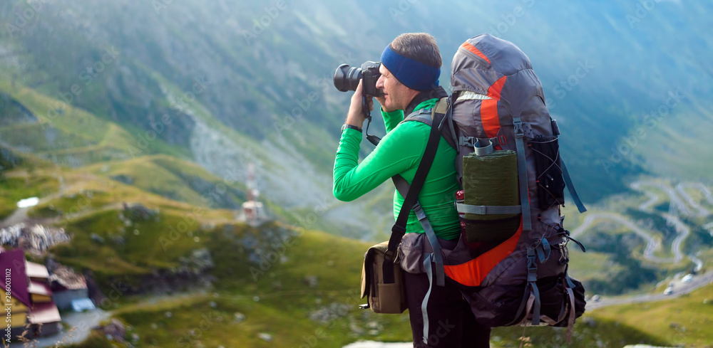 man with backpack on the mountain. photographer taking photos