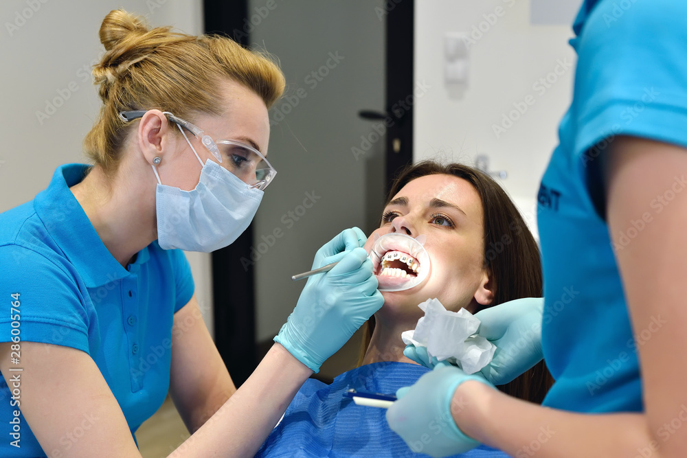 Dentist And Assistant Examine Patient With Braces In Dental Office. Health Care Concept Dentist And Assistant Examine Patient With Braces In Dental Office. Health Care Concept