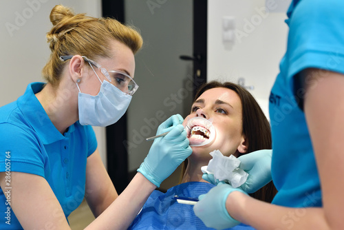 Dentist And Assistant Examine Patient With Braces In Dental Office. Health Care Concept
