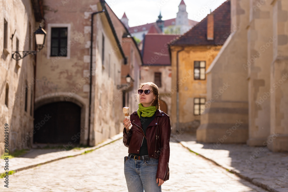 Girl and ice cream. Walk through Bratislava. Leather jacket and sunglasses. Sun in her hair and a green scarf. On the old street.