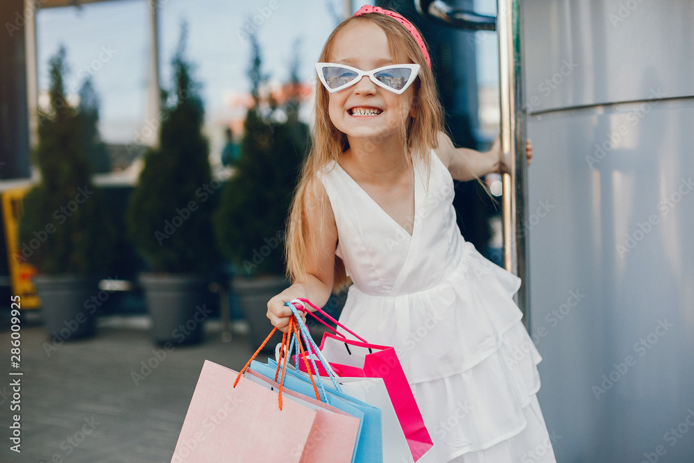 Beautiful girl in a summer city. Child with shopping bags Beautiful girl in a summer city. Child with shopping bags