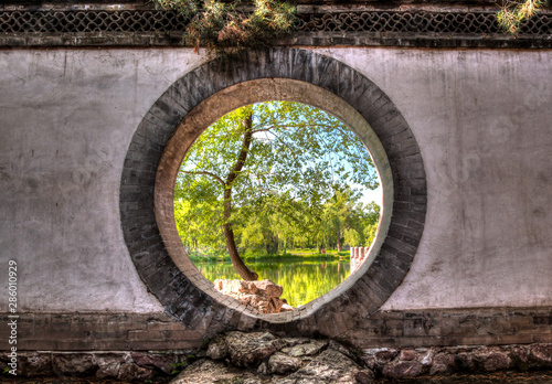Looking through a circular doorway to a lake at Bishushanzhuang Imperial Mountain Resort. photo